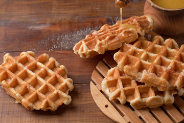 Honey pouring on a fresh waffles. Breakfast with waffles