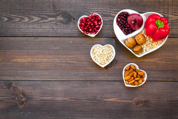 Food which help heart stay healthy. Vegetables, fruits, nuts in heart shaped bowl on dark wooden...