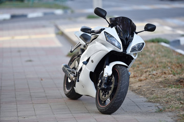 A parked sports bike is standing on the sidewalk in the city. The sports motorcycle is black and...