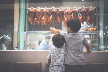 2 hungry brothers are watching a chef preparing roasted duck