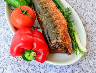 Carcass of the baked fish with fresh vegetables.