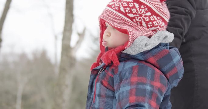 Toddler with frowny face walking in park with mother  - close up