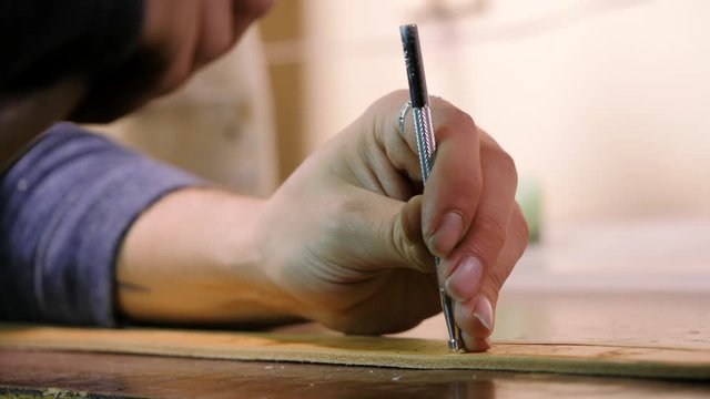 Leather master manufacturer working. Craftsman knocks with hammer to stick two parts. Manufacture goods at home. Close up hands using instrument. Slow motion.