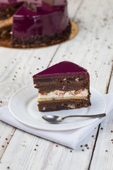 dark chocolate vegan cake with cream and fruit mirror glaze on wooden background