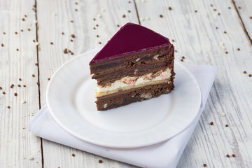 dark chocolate vegan cake with cream and fruit mirror glaze on wooden background