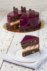 dark chocolate vegan cake with cream and fruit mirror glaze on wooden background