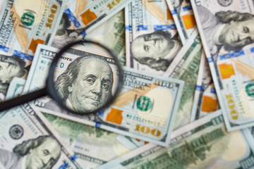 Hundred dollar banknotes under magnifying glass