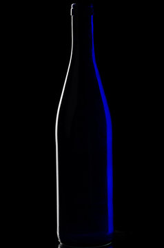 Bar, resturunt and party concept: close-up image of Close-up image. Bottle on a dark background with blue glare on the sides.