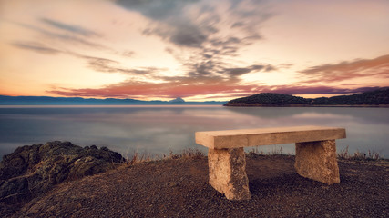 Stone bench at sunset. Beautiful sunset over the Aegean sea, Peninsula Kassandra, Halkidiki,...
