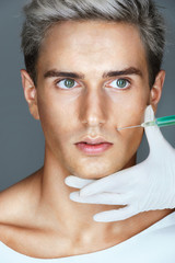 Beautiful Man getting Botox injection in the nasolabial folds. Professional cosmetician making rejuvenate injection. Beauty concept