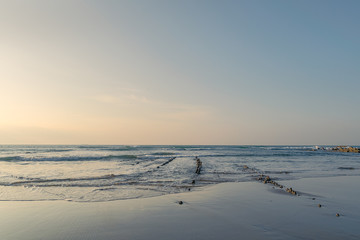 path of sharp rocks forward to the deep sea with reflections in the sand.