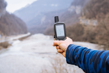 Hand held outdoor GPS being used for navigation in the mountains on the background of the river