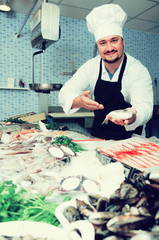 Positive seller shows hands fish on counter