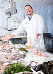 Adult positive man standing near fish counter