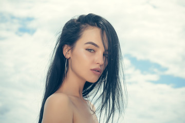 Woman with long brunette hair, hairstyle, on cloudy sky