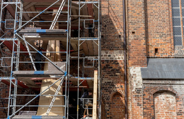 scaffolding with church spire / Scaffolding in front of the wall of a gothic brick church with the unfinished church spire