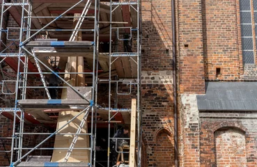 Printed roller blinds Monument scaffolding with church spire / Scaffolding in front of the wall of a gothic brick church with the unfinished church spire
