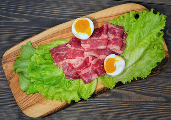 Raw meat, marbled beef thin slices with salad and egg, on a board of natural wood