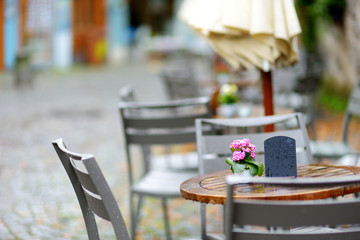 Empty outdoor cafe on beautiful rainy autumn day in Lindau, Germany. Empty chiars and tables under falling rain in autumn.
