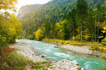 Picturesque blue river flowing through autumn forest in Berchtesgaden area, Germany.