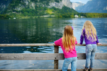 Fototapeta premium Two girls enjoying the scenic view of Hallstatt lakeside town in the Austrian Alps in beautiful evening light on beautiful day in autumn