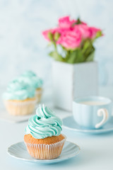 Blue pastel vertical banner with decorated cupcakes, cup of coffe with milk and bouquet of pink roses.