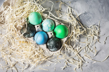 Fototapeta na wymiar painted eggs in tray, chicken eggs, paint and brush on concrete surface, Easter decorations. Top