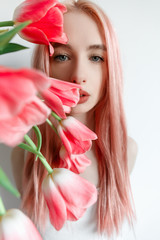 Obraz na płótnie Canvas Portrait of a girl with pink hair pink spring flowers