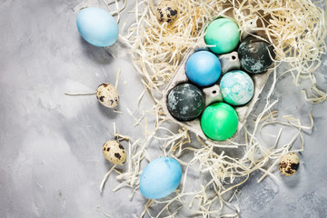 Fototapeta na wymiar painted eggs in tray, quail and chicken eggs, paint and brush on concrete surface, Easter decorations
