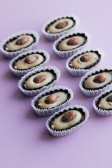 Composition of delicious praline sweets with almonds on purple background