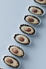 Composition of delicious praline sweets with almonds on blue background