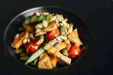 Fresh healthy dinner with seeds and vegetables on black plate