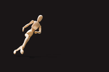 Wooden model on the run. Wooden mannequin in a running pose. Morning running, training. Jogging. The figure of wood runs on a dark gray background. Concept of caring for physical condition.