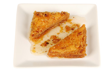 Traditional oriental dessert baklava with syrup. Two pieces of baklava on plate, isolated.