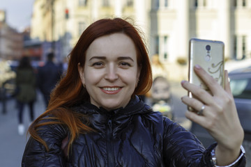 The girl is making a selfie in the city.