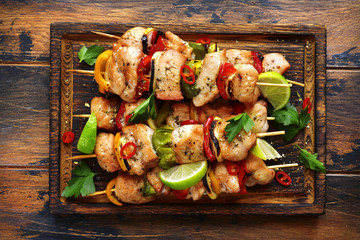 Grilled chicken kebab (skewers) with vegetables on a cutting wooden board.Top view .