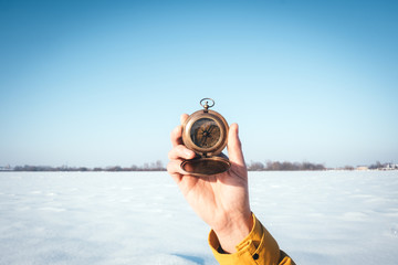 Man with compass in hand on snowy winter field. Travel concept
