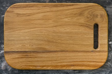 New wooden oak cutting board, rustic black background. Background for the menu, text
