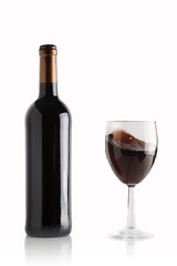 glass of red wine with full bottle on white background