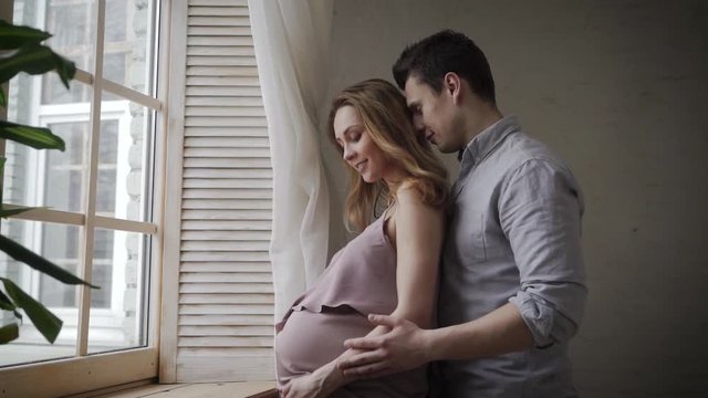 Pregnancy moents. Husband is hugging his pregnantt wife.
