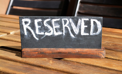 Reserved table. The reserved logo. Booking badge. Wooden reservation sign. Reserved table in the restaurant. Hungry. Busy.