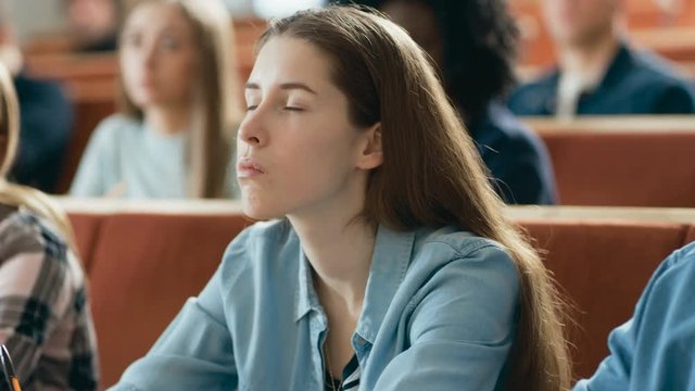Beautiful Young Girl Listening to a Lecture in a Classroom. Diverse Group of Multi Ethnic Students Study at the University. Shot on RED EPIC-W 8K Helium Cinema Camera.