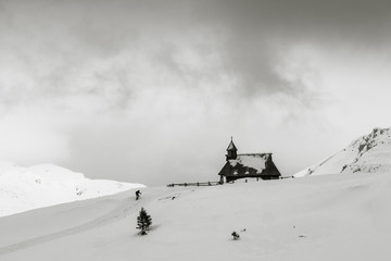 Fototapeta na wymiar Typical cottage and the church of Snowy Mary on Velika planina, Slovenia