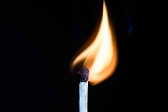 Match with flames in the shape of the upper side of the bulb on a black background closeup