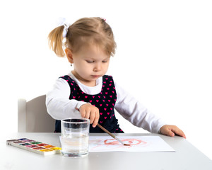 A little girl is drawing at the table.