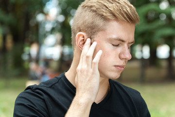 Man suffering from otitis in park
