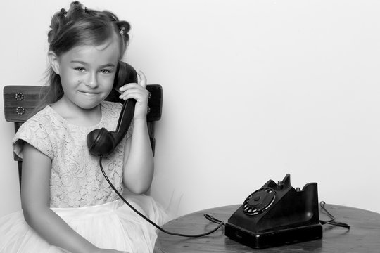A little girl is ringing on the old phone.