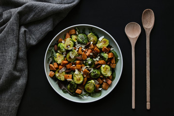 vegetable dish in plate with spoon flat lay on black background