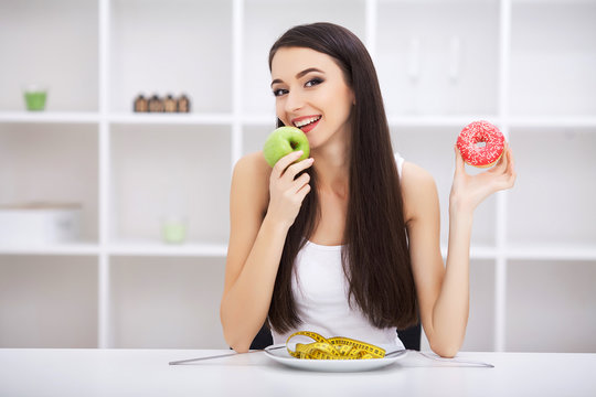 Dieting concept, beautiful young woman choosing between healthy food and junk food
