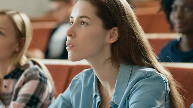 Beautiful and Intelligent Young Girl Listens to a Lecture in a Classroom Full of Multi Ethnic Students. Shallow Depth of Field.Shot on RED EPIC-W 8K Helium Cinema Camera.